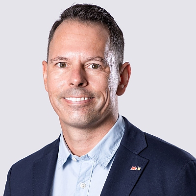 Ein lächelnder Mann im blauen Sakko und hellblauen Hemd