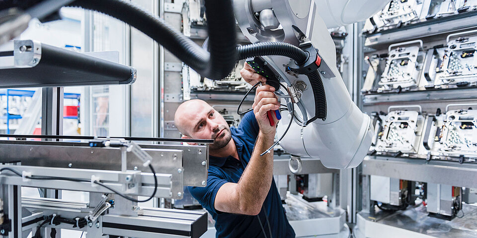 Techniker justiert präzise einen Industrieroboter in einer hochmodernen Produktionshalle.