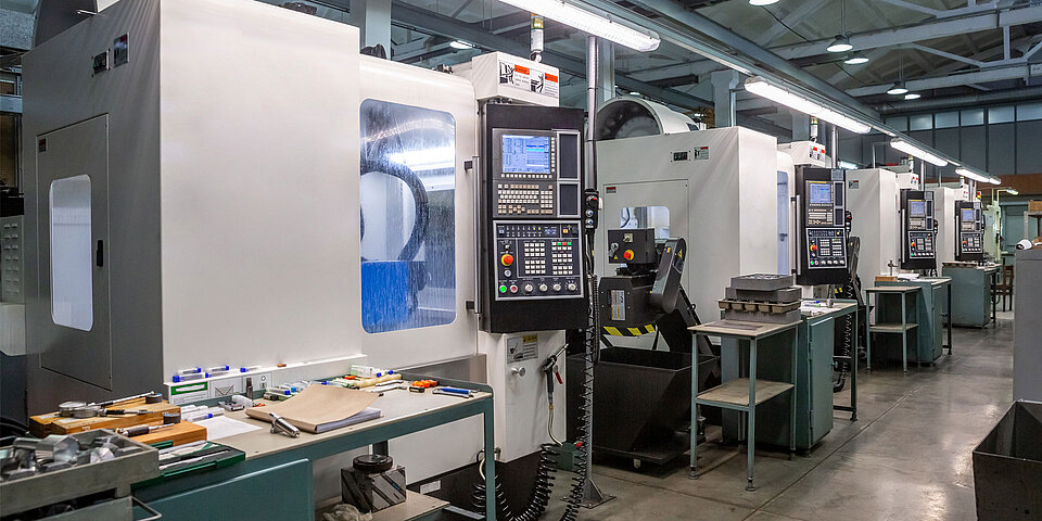 Moderne CNC-Drehmaschinen in einer gut ausgestatteten Metallbearbeitungswerkstatt mit Arbeitsplätzen und Werkzeugen.